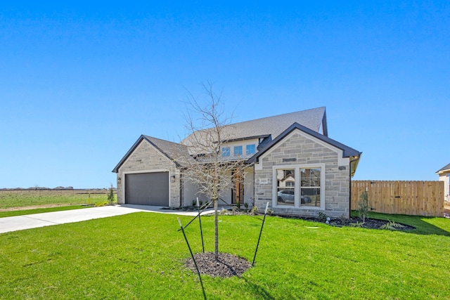 view of front facade with a front lawn, driveway, stone siding, fence, and an attached garage