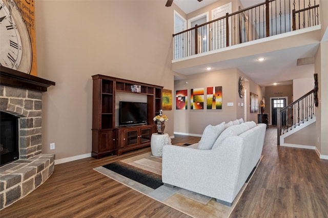 living room with a stone fireplace, ceiling fan, and hardwood / wood-style flooring