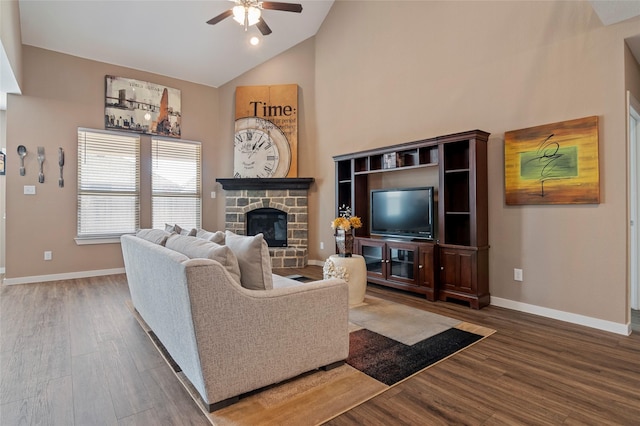 living room with ceiling fan, a stone fireplace, dark hardwood / wood-style floors, and high vaulted ceiling