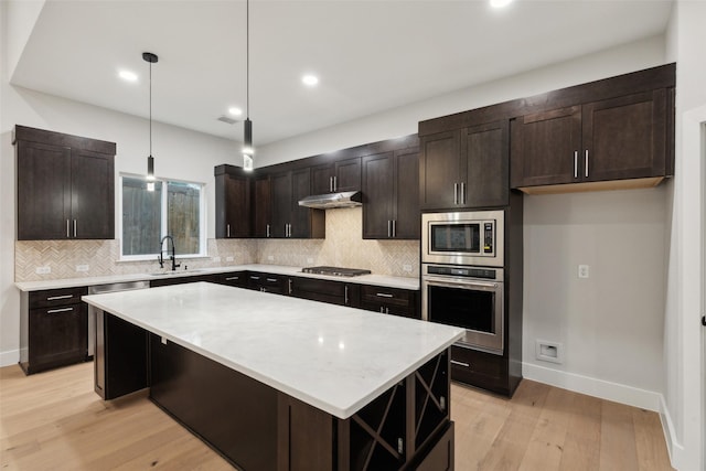 kitchen with sink, a center island, dark brown cabinets, appliances with stainless steel finishes, and pendant lighting