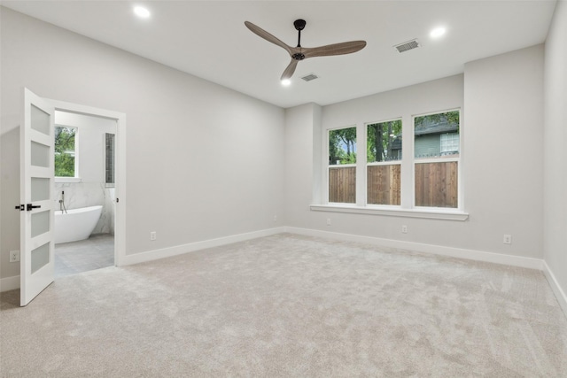 unfurnished bedroom featuring connected bathroom, light colored carpet, and ceiling fan