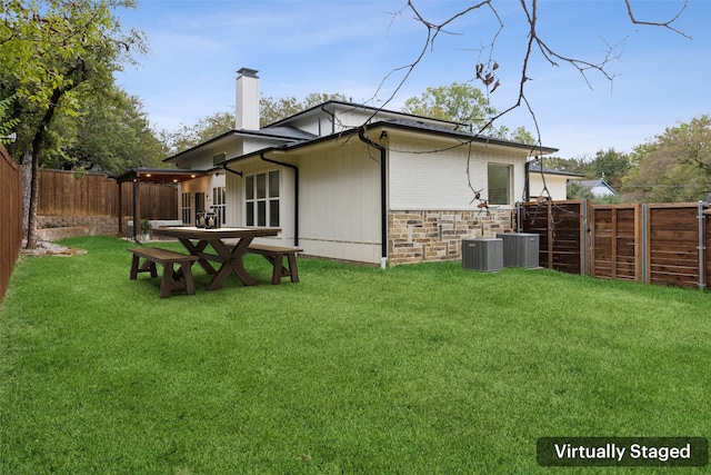 rear view of property with central AC unit and a lawn