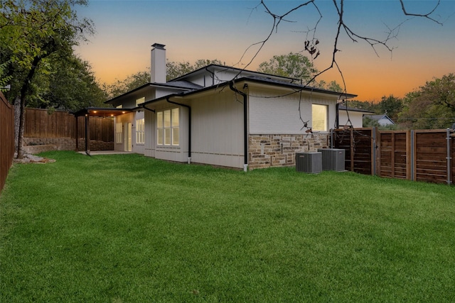 property exterior at dusk featuring central AC and a lawn