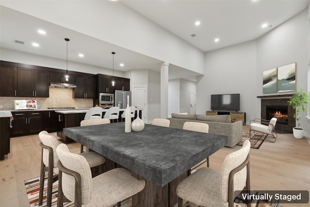 dining area with a high ceiling and light hardwood / wood-style floors