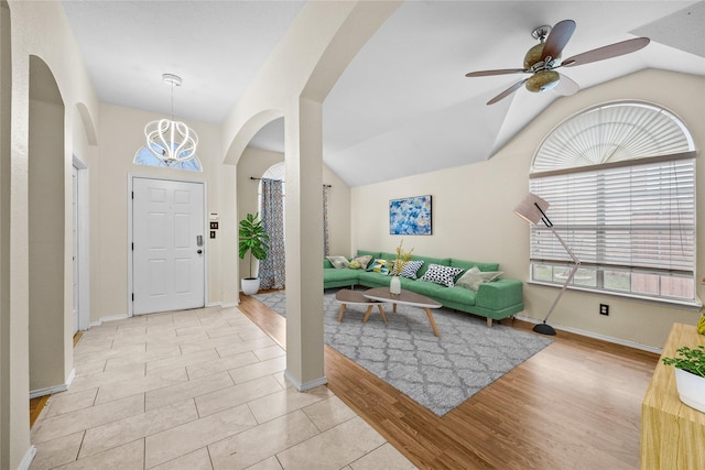 foyer entrance featuring lofted ceiling, ceiling fan with notable chandelier, and light hardwood / wood-style flooring