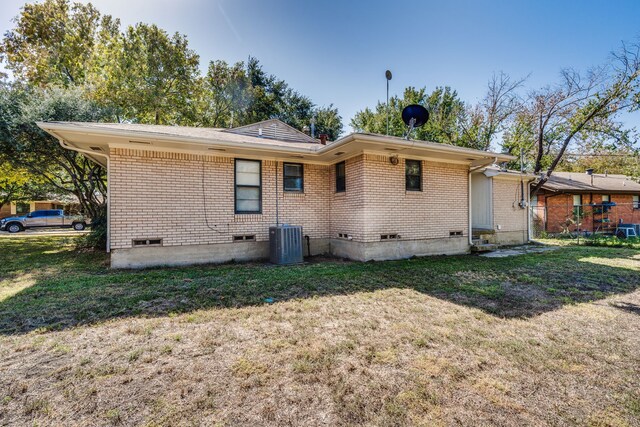 back of property with central AC and a lawn