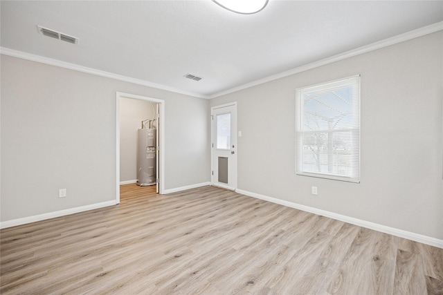 spare room with light wood-type flooring, electric water heater, crown molding, and visible vents