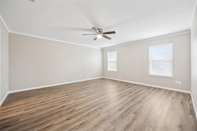 empty room with baseboards, ceiling fan, wood finished floors, and crown molding