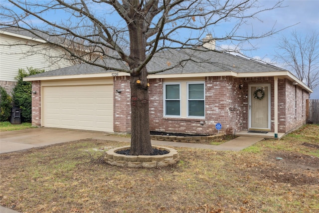 ranch-style home featuring concrete driveway, roof with shingles, an attached garage, brick siding, and a chimney