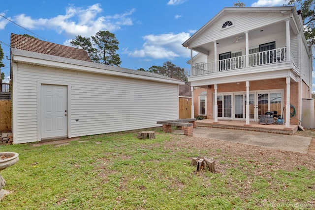 rear view of property featuring a patio, a balcony, and a lawn