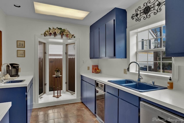 kitchen featuring sink, dishwashing machine, and blue cabinetry