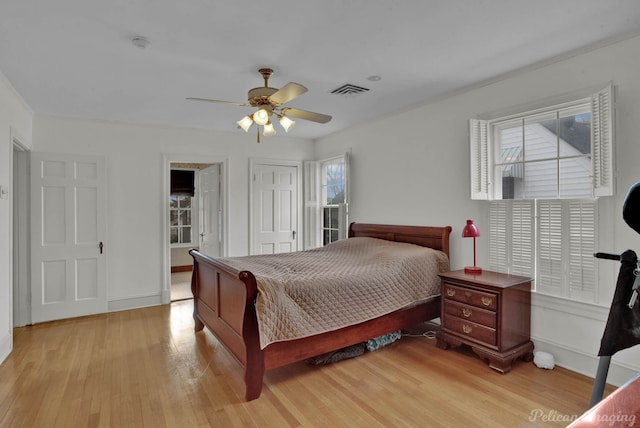 bedroom with ceiling fan, multiple windows, a closet, and light hardwood / wood-style flooring