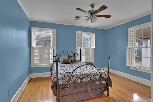 bedroom with crown molding, light hardwood / wood-style flooring, and ceiling fan