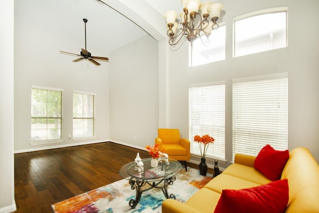 living room with beam ceiling, hardwood / wood-style flooring, ceiling fan with notable chandelier, and a towering ceiling