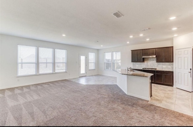 kitchen with visible vents, open floor plan, light carpet, decorative backsplash, and gas cooktop