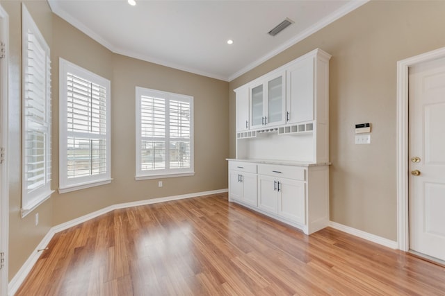 interior space featuring crown molding, light hardwood / wood-style flooring, and white cabinets