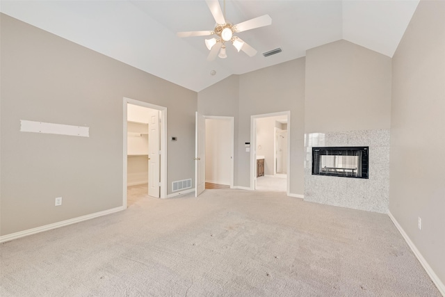 unfurnished living room featuring a tiled fireplace, high vaulted ceiling, light colored carpet, and ceiling fan