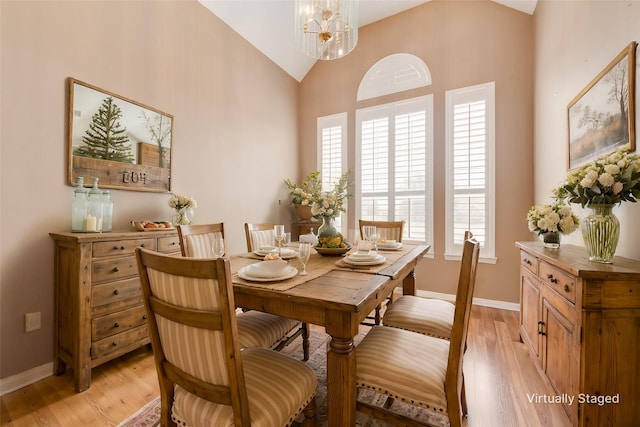 dining space featuring lofted ceiling, a chandelier, and light hardwood / wood-style floors