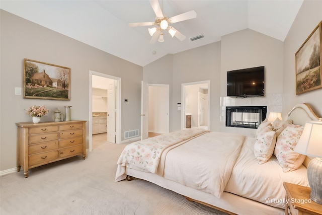 bedroom with connected bathroom, light colored carpet, vaulted ceiling, a multi sided fireplace, and ceiling fan