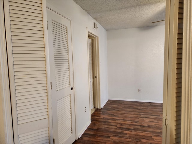 corridor featuring dark hardwood / wood-style floors and a textured ceiling