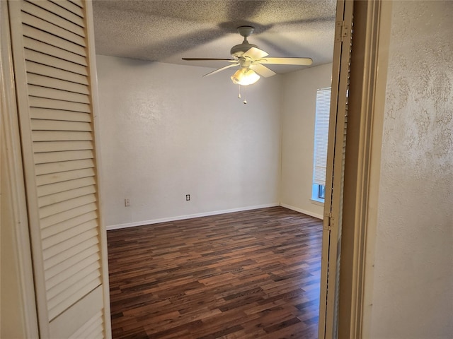 empty room with ceiling fan, dark wood-type flooring, and a textured ceiling