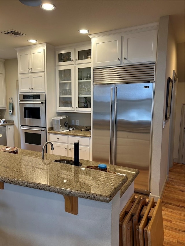 1434 Lakeside Trl, Whitney, TX 76692 - kitchen with stainless steel appliances, white cabinetry, a breakfast bar area, and dark stone counters