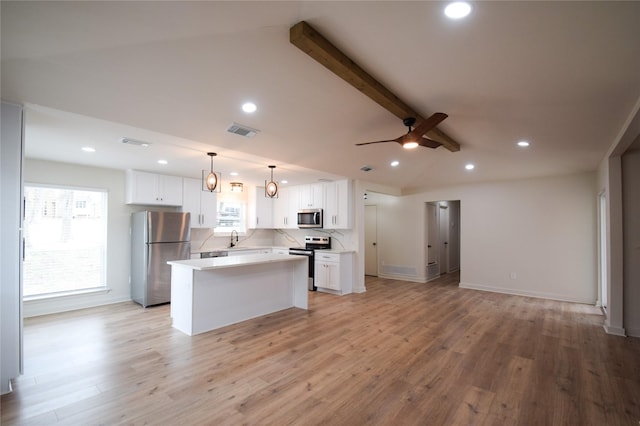 kitchen with vaulted ceiling with beams, a kitchen island, decorative light fixtures, stainless steel appliances, and white cabinets