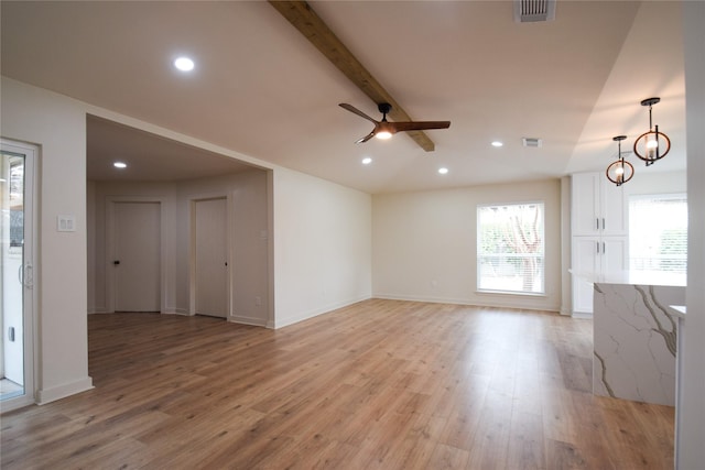 unfurnished living room with light hardwood / wood-style floors, lofted ceiling with beams, and a wealth of natural light