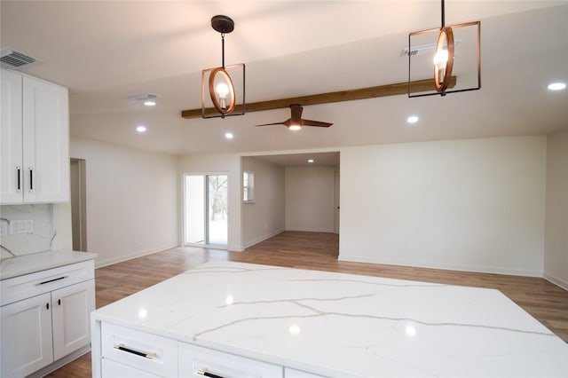 kitchen with pendant lighting, white cabinetry, and light stone counters