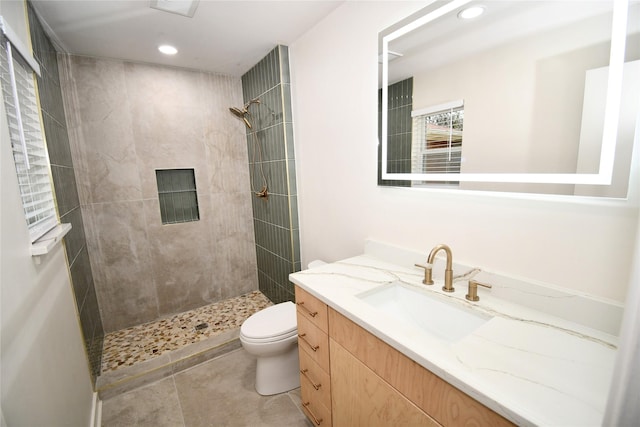 bathroom featuring tile patterned flooring, vanity, tiled shower, and toilet