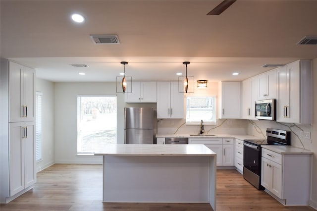 kitchen with white cabinetry, appliances with stainless steel finishes, sink, and hanging light fixtures