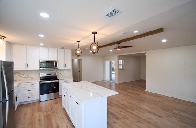 kitchen featuring stainless steel appliances, a kitchen island, backsplash, light stone counters, and white cabinets