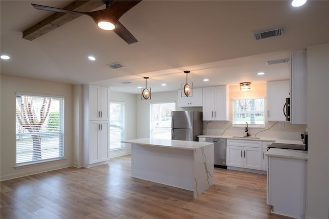 kitchen with white cabinetry, a center island, decorative light fixtures, sink, and appliances with stainless steel finishes