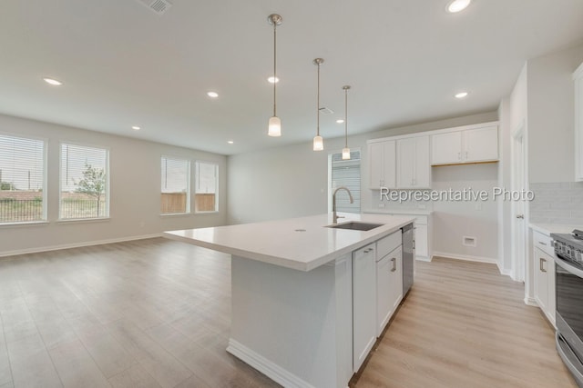 kitchen featuring sink, white cabinetry, decorative light fixtures, a center island with sink, and stainless steel appliances