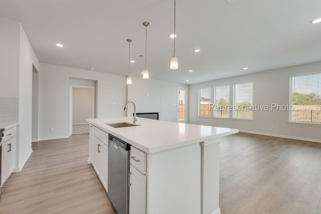 kitchen featuring sink, white cabinetry, a center island with sink, stainless steel dishwasher, and pendant lighting