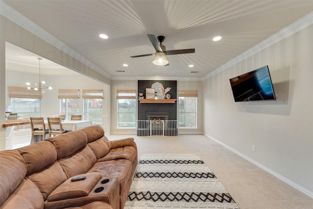 living room featuring a brick fireplace, crown molding, a healthy amount of sunlight, and carpet flooring