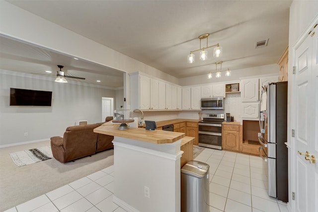 kitchen with appliances with stainless steel finishes, decorative light fixtures, butcher block countertops, and light tile patterned floors