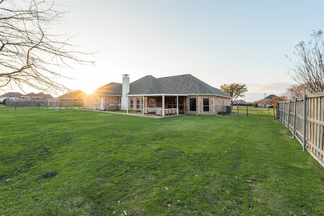 back house at dusk with a patio and a lawn