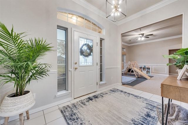 tiled entryway with crown molding and ceiling fan with notable chandelier