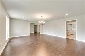 unfurnished room with an inviting chandelier and dark wood-type flooring