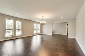 unfurnished room with an inviting chandelier and dark wood-type flooring