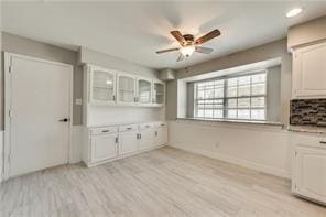 kitchen with white cabinets, ceiling fan, and light hardwood / wood-style flooring