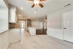 kitchen featuring tasteful backsplash, white cabinetry, ceiling fan, and light hardwood / wood-style flooring