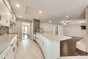 kitchen featuring sink, a center island, white cabinets, light hardwood / wood-style floors, and backsplash