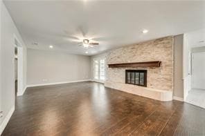 unfurnished living room featuring ceiling fan, a fireplace, and dark hardwood / wood-style flooring