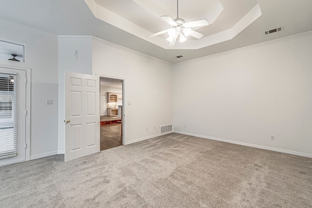 unfurnished room featuring visible vents, a raised ceiling, and carpet flooring