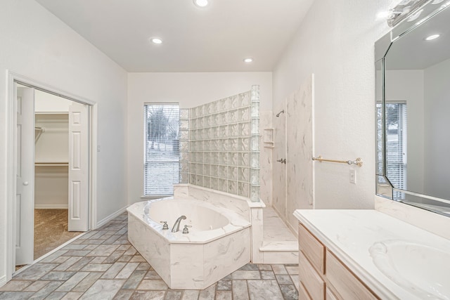 bathroom with recessed lighting, vanity, a walk in closet, a bath, and walk in shower