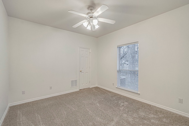 unfurnished room with carpet floors, visible vents, ceiling fan, and baseboards