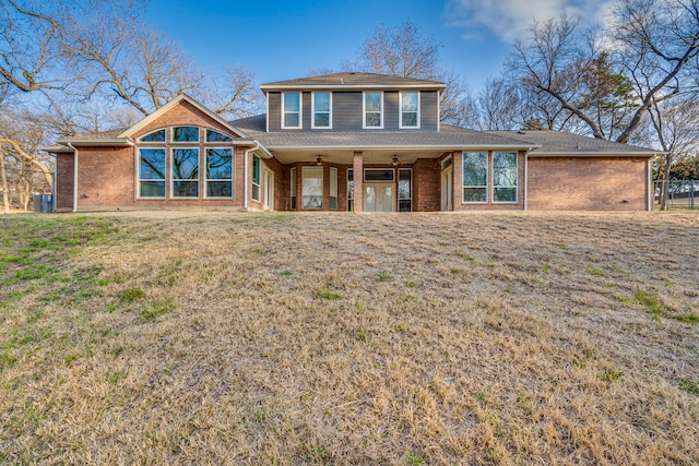 view of front facade with ceiling fan, brick siding, and a front yard