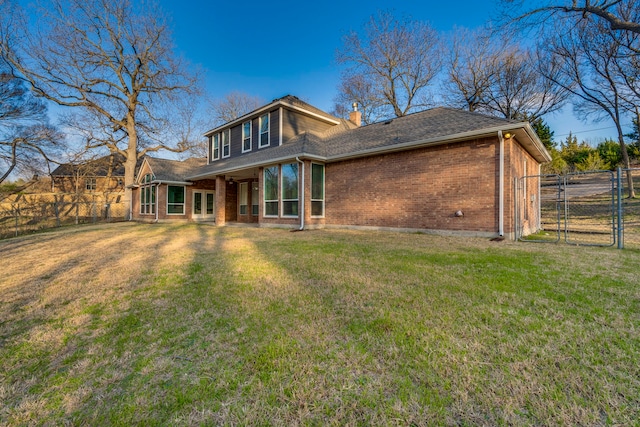 back of property with brick siding, fence, a lawn, a gate, and a chimney